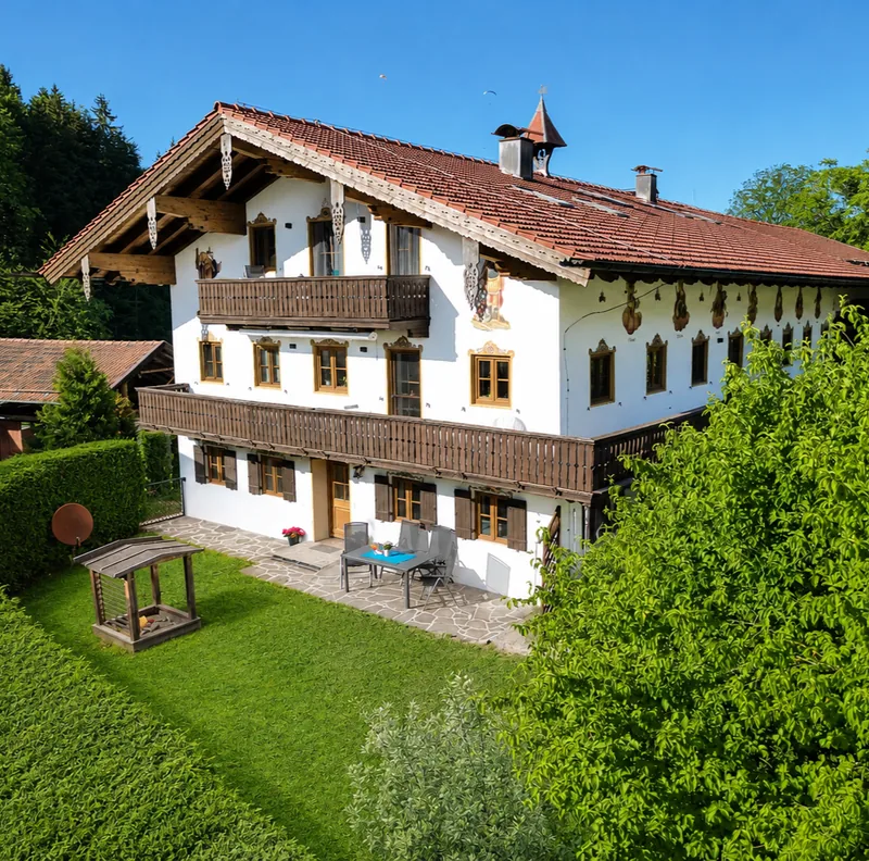 Der Oberschneiderhof am Samerberg von außen: Bauernhaus mit Holzbalkon, Garten und Terrasse